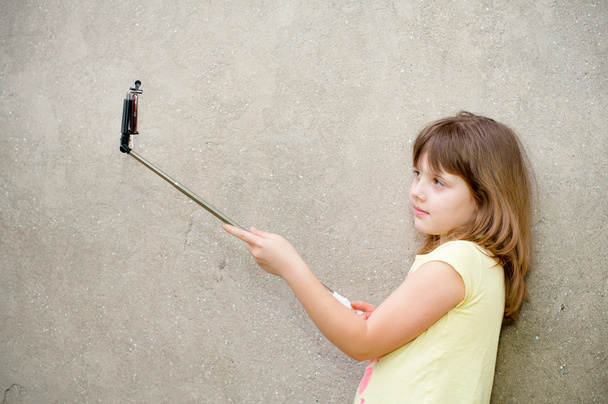 Girl makes selfie with monopod in hands - Φωτογραφία, εικόνα
