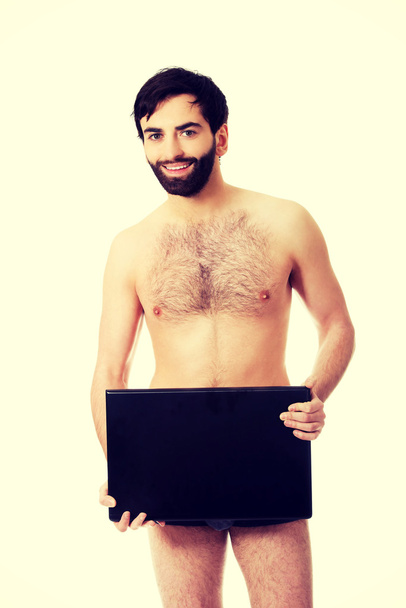 Young shirtless man holding laptop. - Фото, изображение