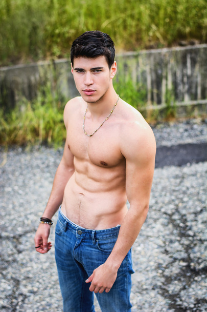 Shirtless muscular young man walking on rural road - 写真・画像