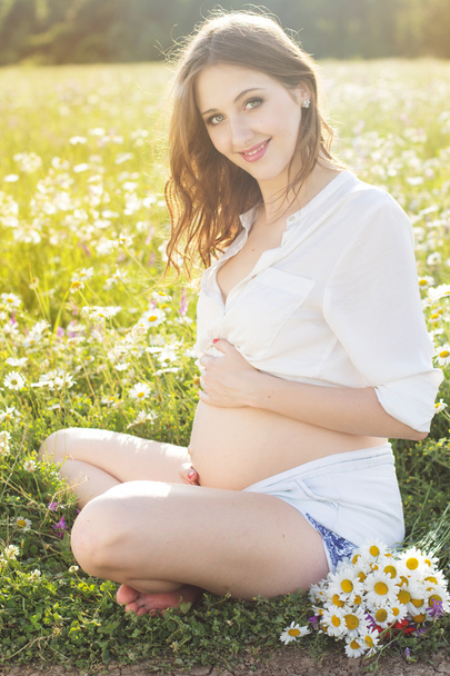 Schwangere lächelnde Frau ruht sich in der Natur aus - Foto, Bild