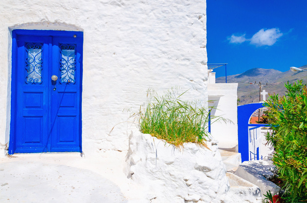 Blauw houten deur, witte muur en bloemen in Griekenland - Foto, afbeelding