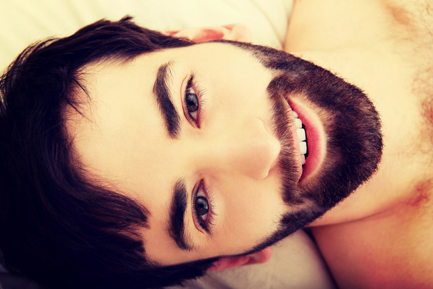 Young muscular man lying in bed. - Fotoğraf, Görsel