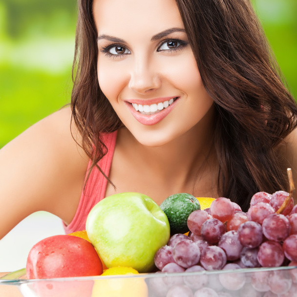 mulher sorridente com prato de frutas, ao ar livre
 - Foto, Imagem