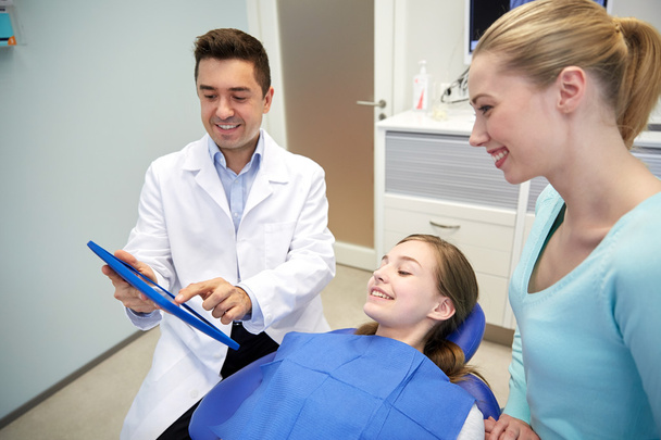 dentist showing tablet pc to girl and her mother - Foto, Bild