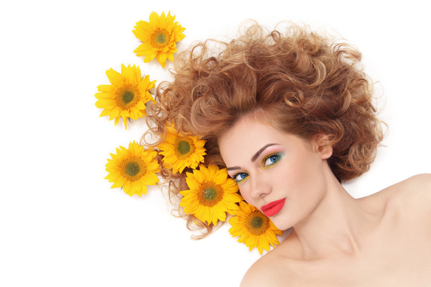 woman with curly hair and sunflowers - Фото, изображение