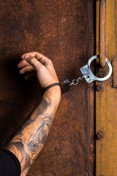 Tätowierte Hand eines Verbrechers in Handschellen - Foto, Bild