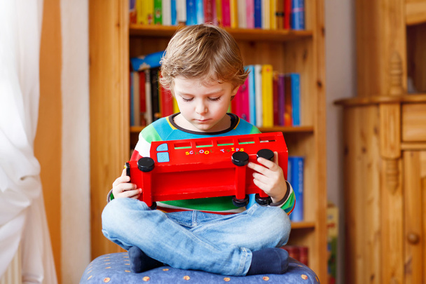 Petit garçon blond jouant avec bus jouet en bois, à l'intérieur
 - Photo, image