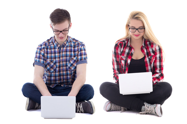 εφηβικό κορίτσι και αγόρι καθιστός με φορητούς υπολογιστές που απομονώνονται σε λευκό - Φωτογραφία, εικόνα