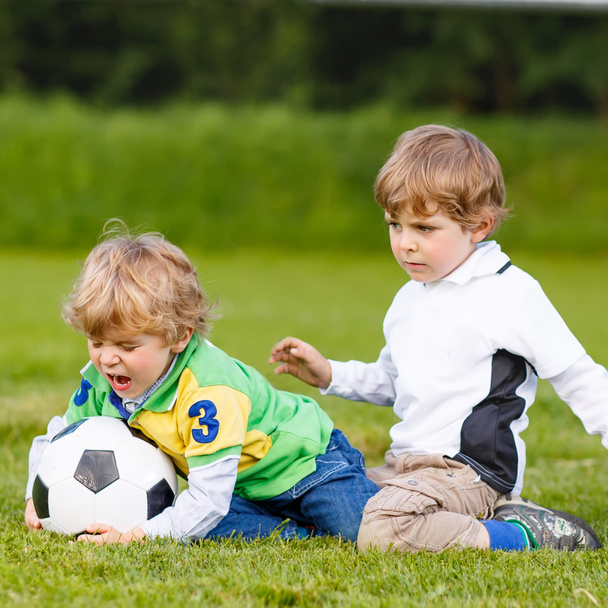Two little sibling boys playing soccer and football - Photo, Image