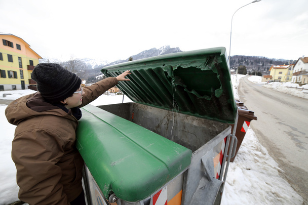 Poor boy tries to eat into the waste box in winter - Φωτογραφία, εικόνα