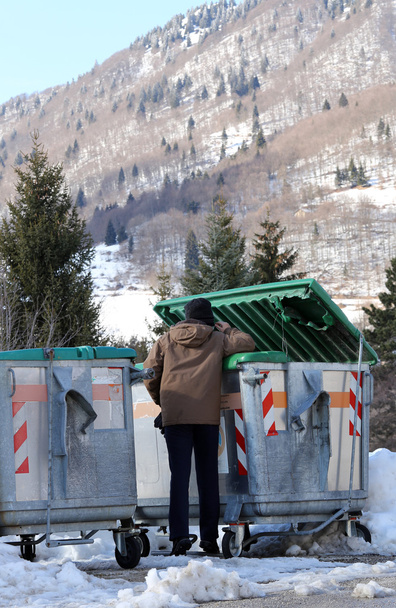 Pobre chico trata de comer en la caja de residuos en invierno
 - Foto, Imagen