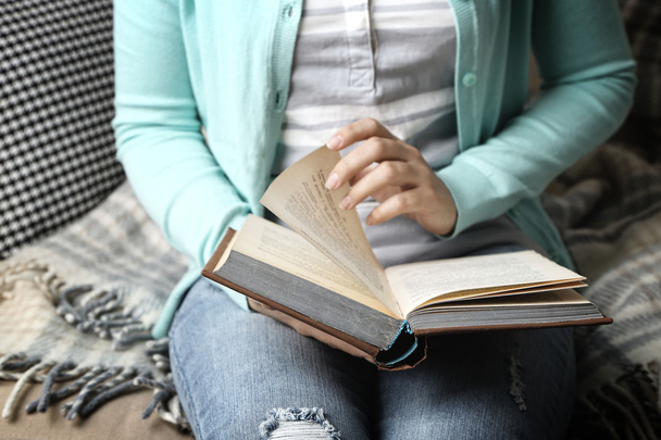 Young woman reading book, close-up, on home interior background - Foto, Imagem