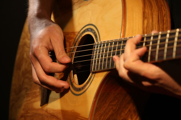 Young man playing on acoustic guitar close up - 写真・画像