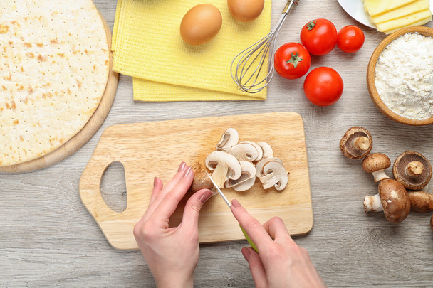 Female hands cooking pizza on wooden table, closeup - Photo, image