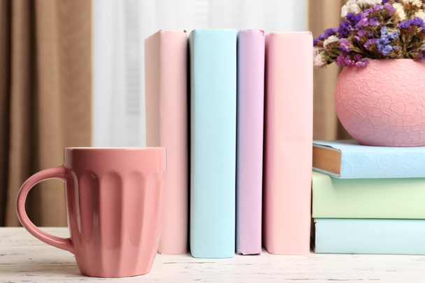 Books, cup and plant on wooden table, closeup - 写真・画像