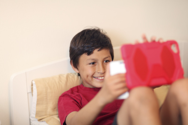 Nuori poika tekee selfie kuvia älypuhelimella ja tabletilla
 - Valokuva, kuva