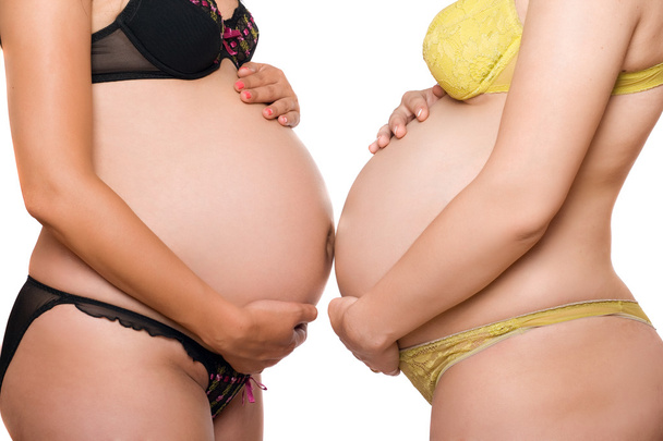 Two bellies of pregnant young women. Isolated - 写真・画像