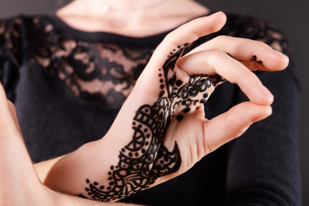 Closeup image of henna on female hand on dark background - Photo, image