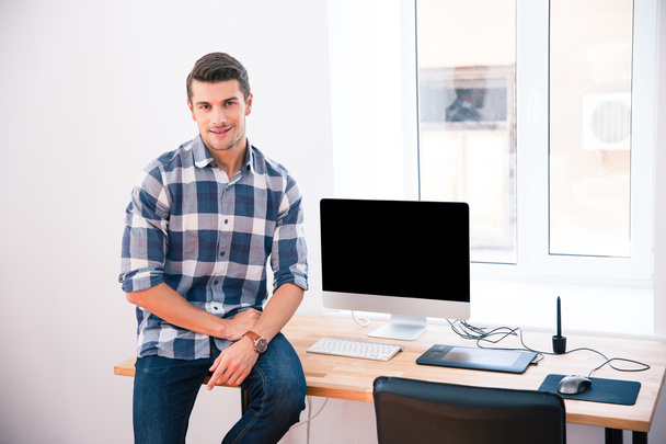 Счастливый бизнесмен сидит на столе
 - Фото, изображение