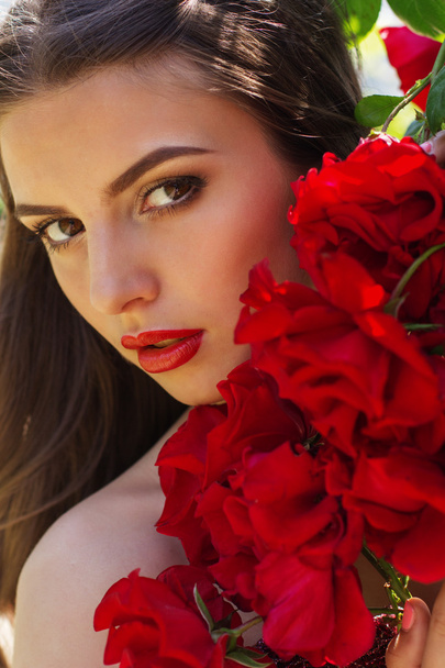 Fashion portrait of beautiful woman is posing near roses  - Φωτογραφία, εικόνα