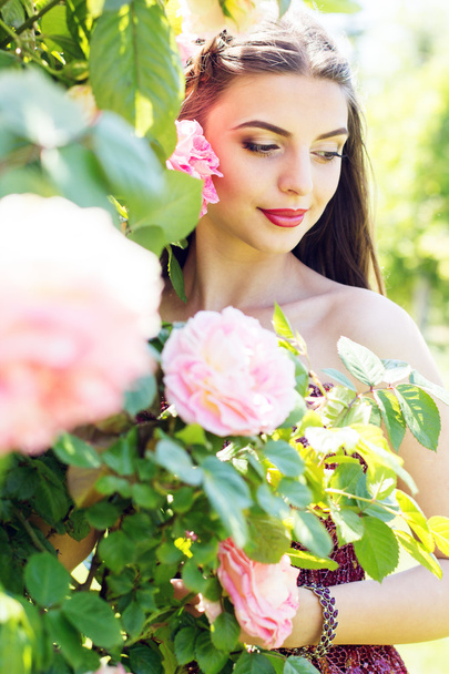 Fashion portrait of beautiful woman is posing near roses  - Zdjęcie, obraz