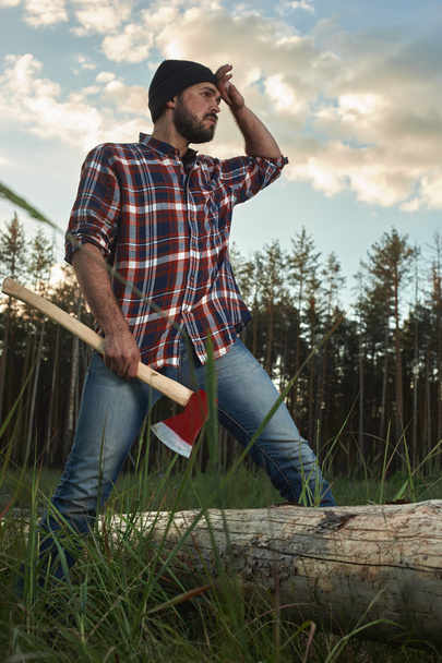 Bearded Lumberjack holding a big Ax in one Hand and wipes the Sw - Φωτογραφία, εικόνα