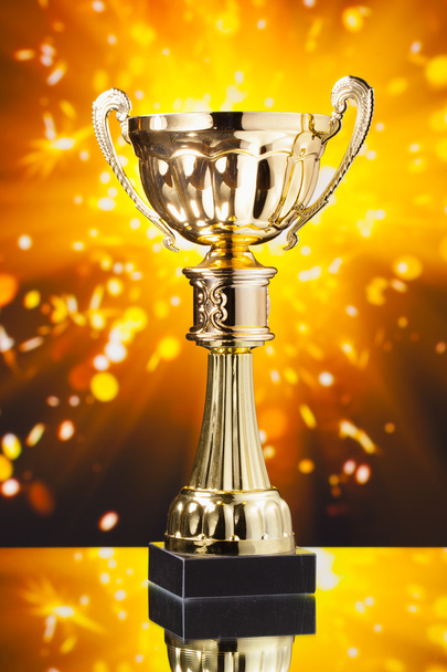 Gold cup trofee tegen glanzende sparks achtergrond - Foto, afbeelding