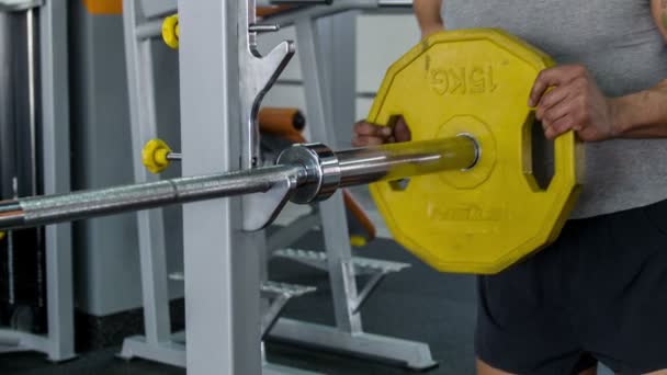 Handsome sportsman is putting weight on iron equipment - Filmati, video