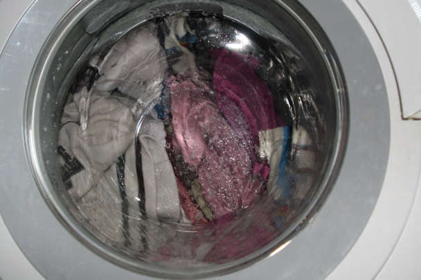 Прання брудного прання в пральній машині всередині будинку
 - Фото, зображення