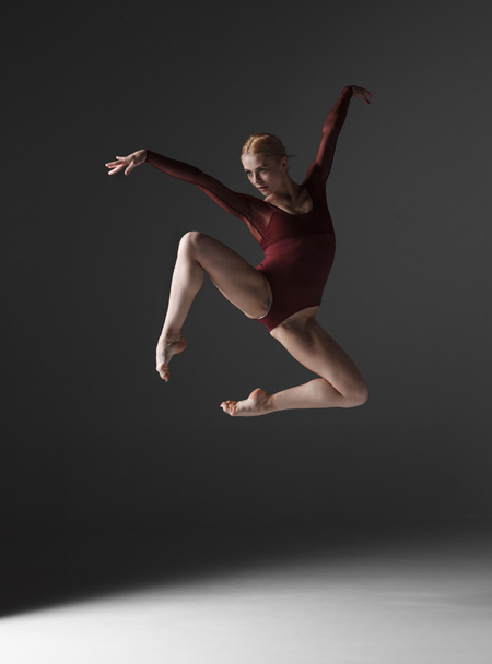 Young beautiful modern style dancer jumping on a studio background - Foto, imagen