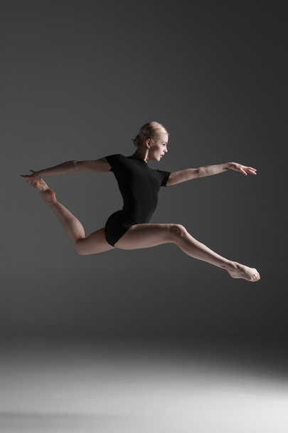 Young beautiful modern style dancer jumping on a studio background - Zdjęcie, obraz