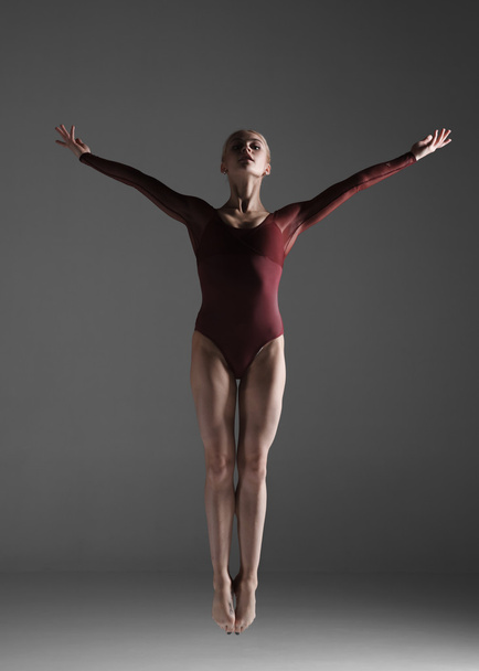 Young beautiful modern style dancer jumping on a studio background - Valokuva, kuva