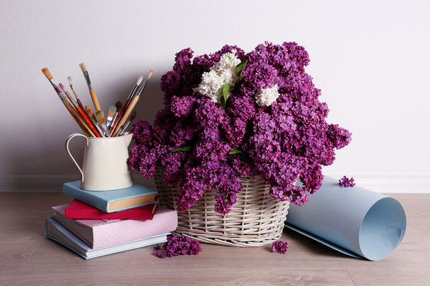Beautiful lilac flowers on basket on floor in room close-up - Foto, Imagen