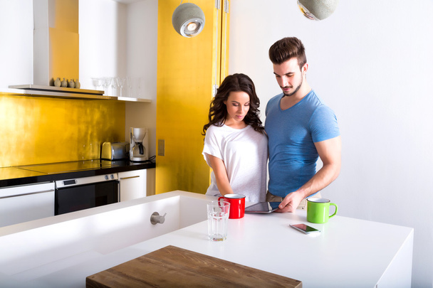Young couple using a Tablet PC in the kitchen at home - Photo, Image