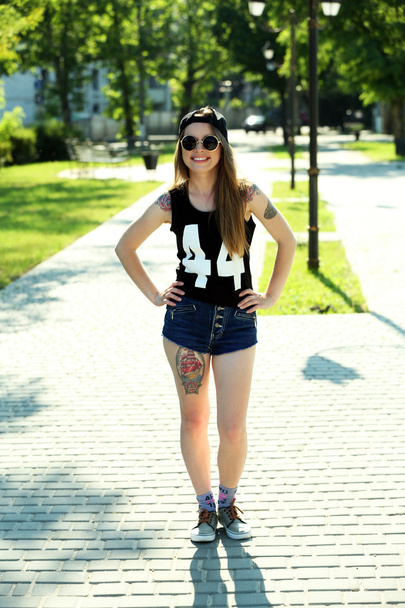 Beautiful girl with stylish make-up and tattooed body outdoors - 写真・画像
