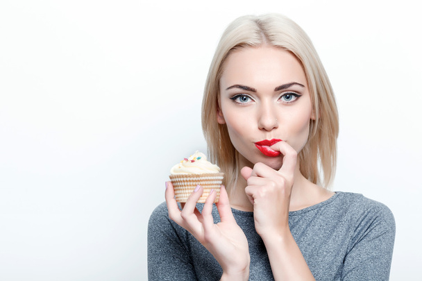 Pretty young woman tasting cupcake - Foto, afbeelding