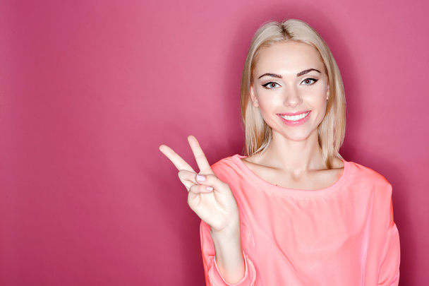 Smiling blond-haired woman pointing with fingers - Foto, imagen