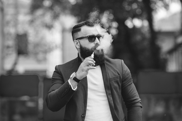 άνδρας με μούσι καπνίζει το ηλεκτρονικό τσιγάρο - Φωτογραφία, εικόνα