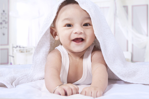 Innocent baby laughing on the bed alone - Fotoğraf, Görsel