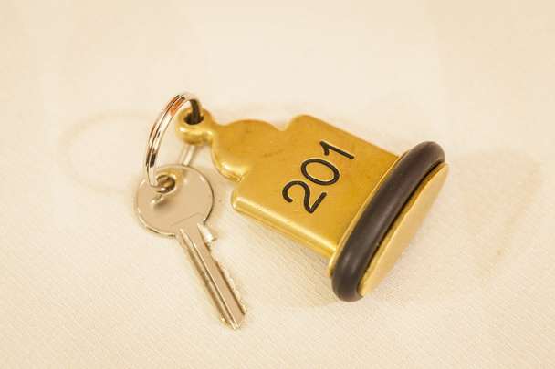 Hotelzimmerschlüssel auf Bett liegend mit Schlüsselanhänger - Foto, Bild