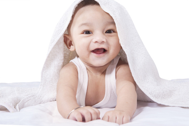 Sweet baby under a towel lying on bed - Valokuva, kuva