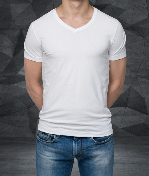 Close up of the body view of the man in a white t-shirt. Hands are crossed behind the back. Contemporary office background. - Photo, Image