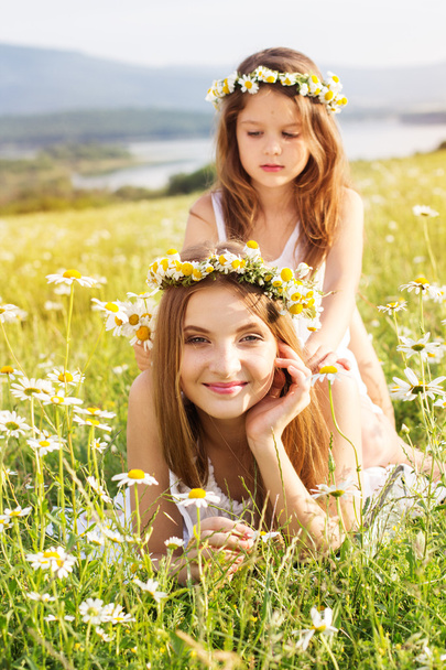 Two pretty girls at meadow with mountain view and flowers - Photo, image