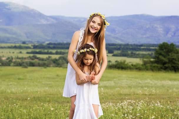 Cute girls at meadow with nice mountain view - Foto, imagen
