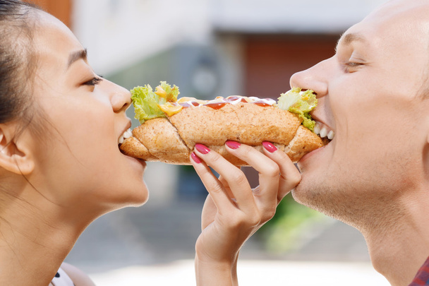 Man and woman biting same hotdog  - Фото, изображение