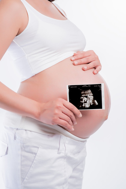 pregnant woman holding ultrasound scan on her tummy - Foto, Imagem