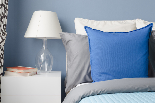oreiller bleu sur lit avec lampe en verre sur table blanche en bleu moderne
 - Photo, image