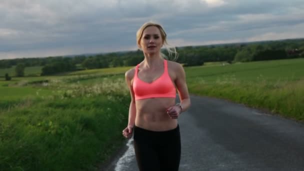bonita mulher loira correndo e se exercitando no campo durante o pôr do sol
 - Filmagem, Vídeo
