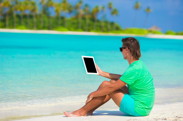 νεαρός άνδρας που εργάζονται με το laptop στην τροπική παραλία - Φωτογραφία, εικόνα