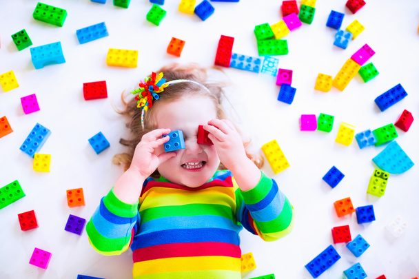 Маленька дівчинка грає з барвистими блоками іграшок
 - Фото, зображення